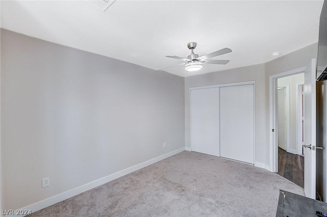 unfurnished bedroom featuring light colored carpet, a closet, and ceiling fan