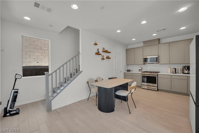 kitchen with stainless steel appliances, gray cabinetry, and light hardwood / wood-style floors