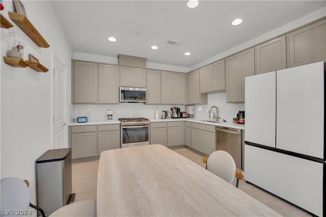 kitchen with sink, light wood-type flooring, gray cabinetry, and stainless steel appliances