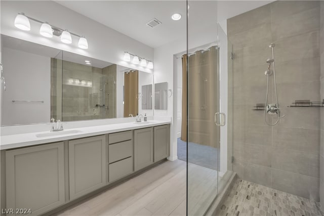 bathroom featuring a shower with shower door and dual vanity