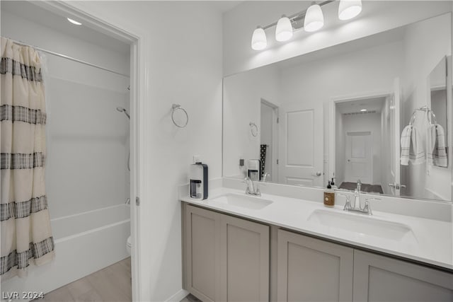 full bathroom featuring dual vanity, toilet, hardwood / wood-style floors, and shower / tub combo