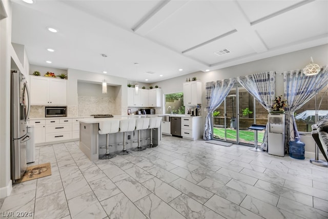 kitchen with a center island, white cabinetry, appliances with stainless steel finishes, tasteful backsplash, and a kitchen bar