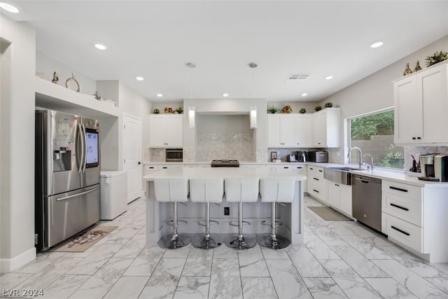 kitchen with tasteful backsplash, white cabinetry, a center island, appliances with stainless steel finishes, and sink