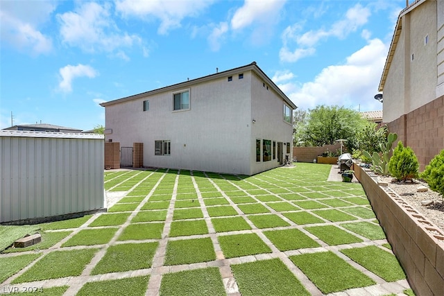 rear view of property with a lawn and a storage shed