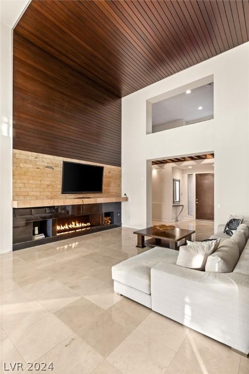 living room with wood ceiling, a fireplace, and a high ceiling