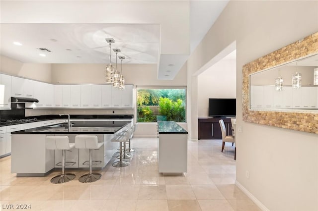 kitchen with white cabinetry, a breakfast bar area, black gas cooktop, and a center island with sink