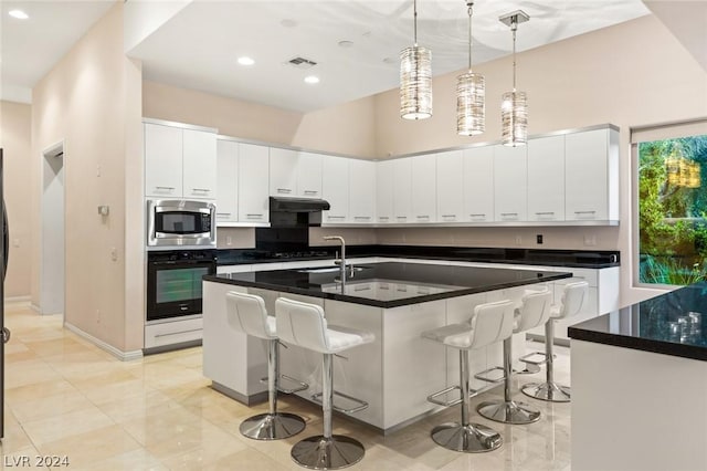 kitchen with a center island with sink, white cabinets, a kitchen breakfast bar, and black appliances