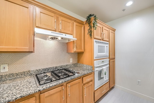 kitchen featuring white appliances, backsplash, and stone countertops