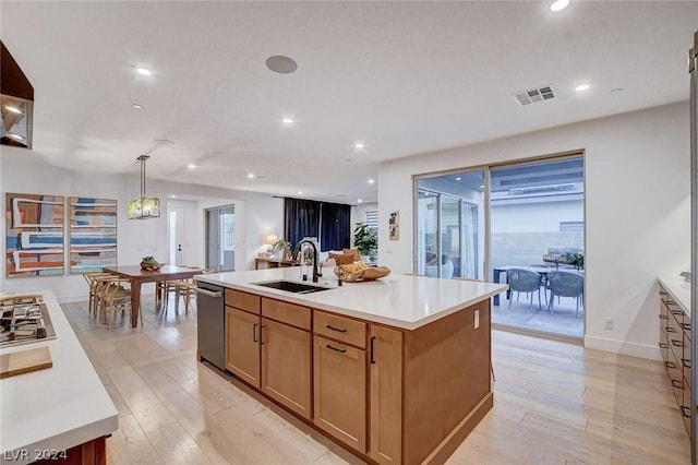 kitchen featuring light hardwood / wood-style floors, appliances with stainless steel finishes, a kitchen island with sink, sink, and decorative light fixtures