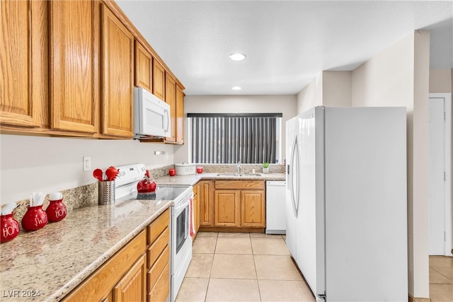 kitchen with sink, light stone counters, white appliances, and light tile patterned floors