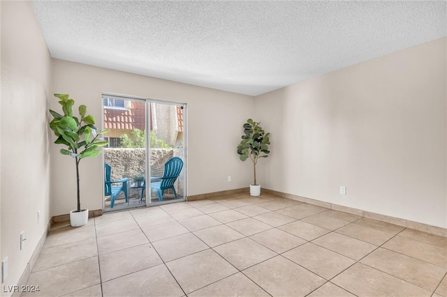 tiled empty room featuring a textured ceiling