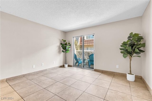 unfurnished room with light tile patterned flooring and a textured ceiling