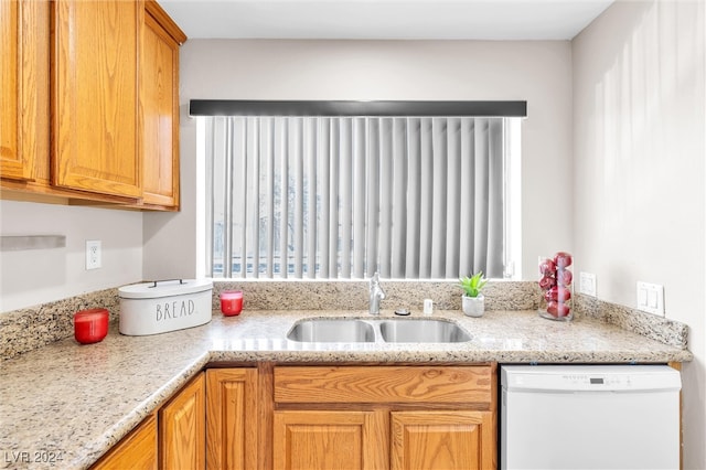 kitchen featuring dishwasher, light stone counters, and sink