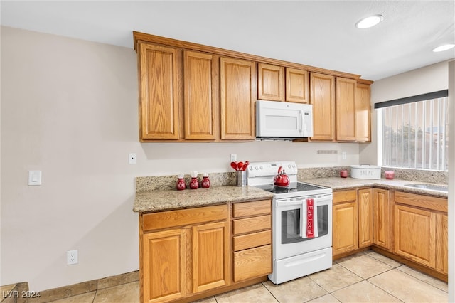 kitchen featuring light stone countertops, white appliances, and light tile patterned floors