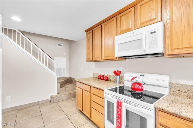 kitchen featuring light tile patterned flooring, light stone countertops, and white appliances