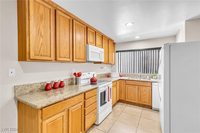 kitchen featuring light tile patterned floors, light stone countertops, white appliances, and sink