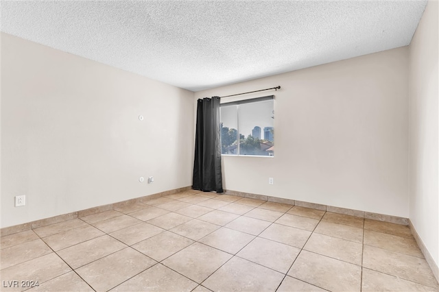 spare room with light tile patterned flooring and a textured ceiling