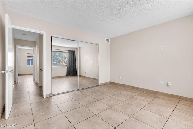 unfurnished bedroom with a closet, light tile patterned floors, and a textured ceiling