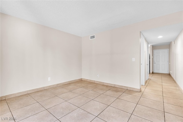 spare room featuring light tile patterned flooring and a textured ceiling