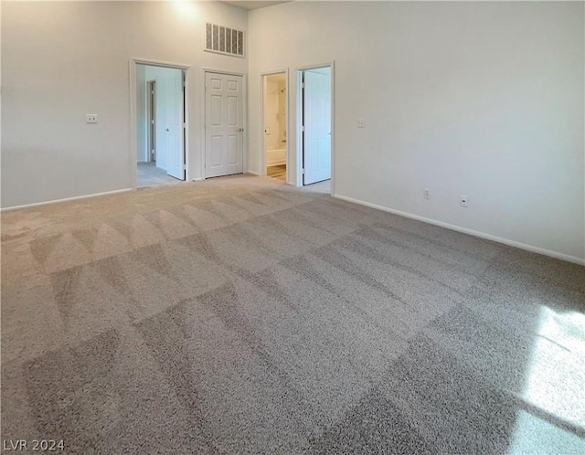 carpeted spare room featuring a towering ceiling