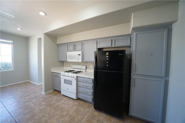 kitchen with gray cabinetry, light tile patterned flooring, and white appliances