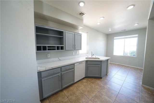 kitchen with gray cabinetry, white dishwasher, sink, light tile patterned floors, and kitchen peninsula