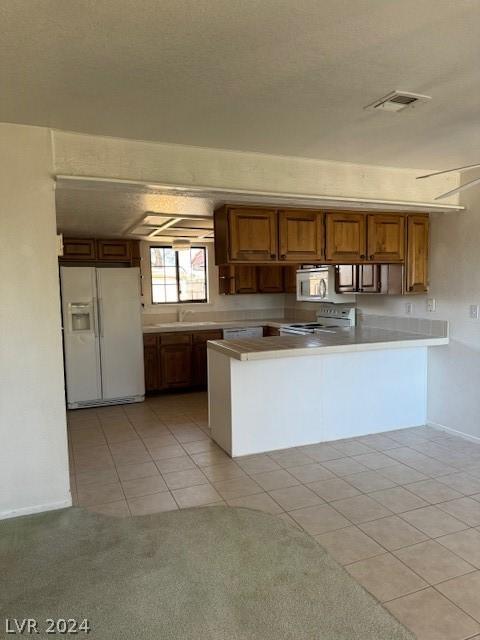 kitchen featuring kitchen peninsula, white appliances, a textured ceiling, light tile floors, and sink