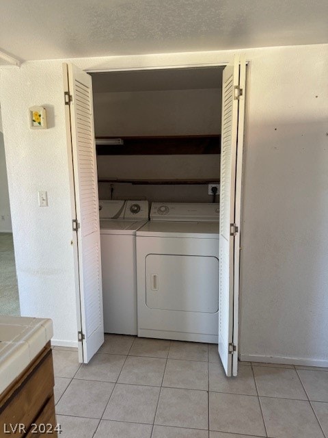 washroom featuring washing machine and clothes dryer and light tile flooring