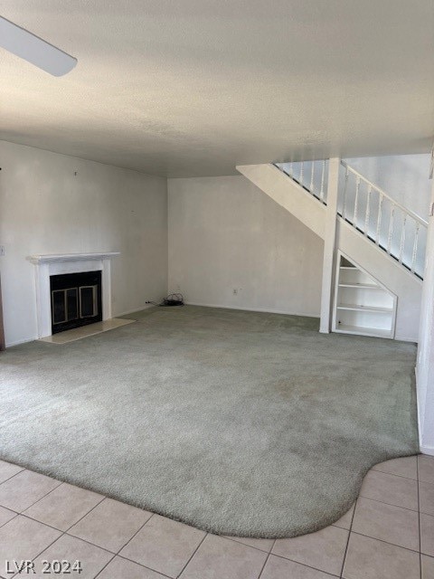 unfurnished living room with built in shelves, a textured ceiling, and light tile flooring