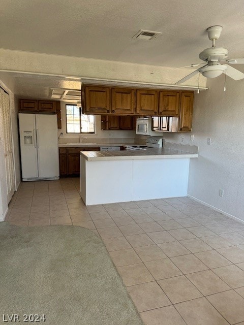 kitchen featuring ceiling fan, kitchen peninsula, white appliances, a textured ceiling, and light tile floors