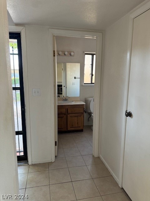 hall featuring sink, a textured ceiling, and light tile floors