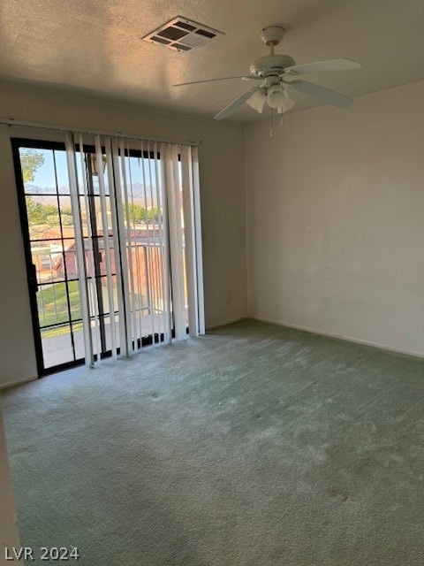 carpeted empty room featuring ceiling fan and a textured ceiling