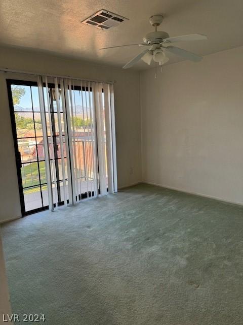 carpeted spare room with ceiling fan and a textured ceiling