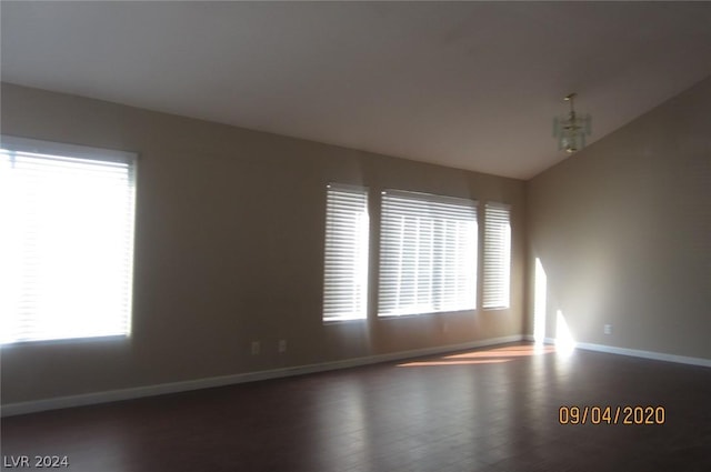 spare room with a chandelier, hardwood / wood-style flooring, and lofted ceiling