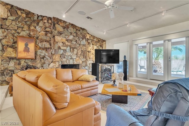 living room featuring light tile patterned floors, rail lighting, a stone fireplace, and ceiling fan