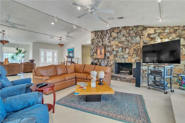 living room with a fireplace, light tile patterned floors, rail lighting, and lofted ceiling