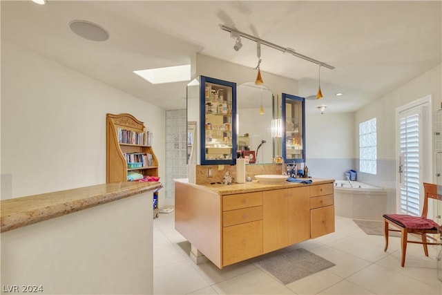 kitchen with light brown cabinets, rail lighting, sink, a skylight, and light tile patterned floors