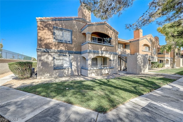 view of front of property featuring a balcony and a front lawn