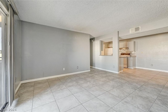 tiled empty room featuring a textured ceiling