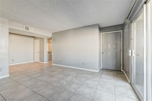 tiled empty room featuring a textured ceiling