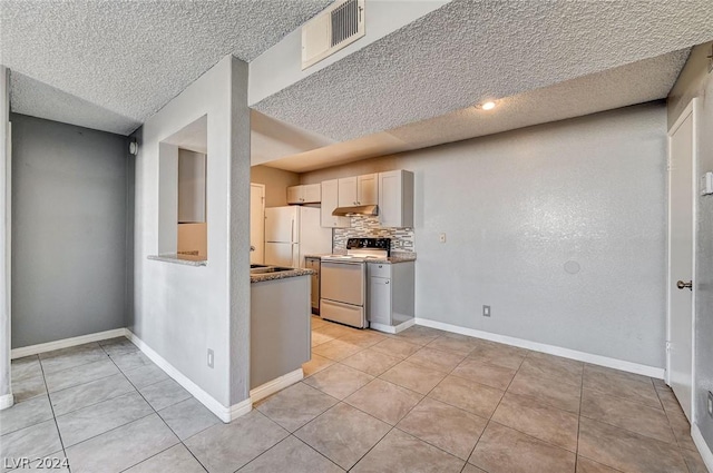 kitchen with light tile patterned floors, white appliances, light stone countertops, and decorative backsplash