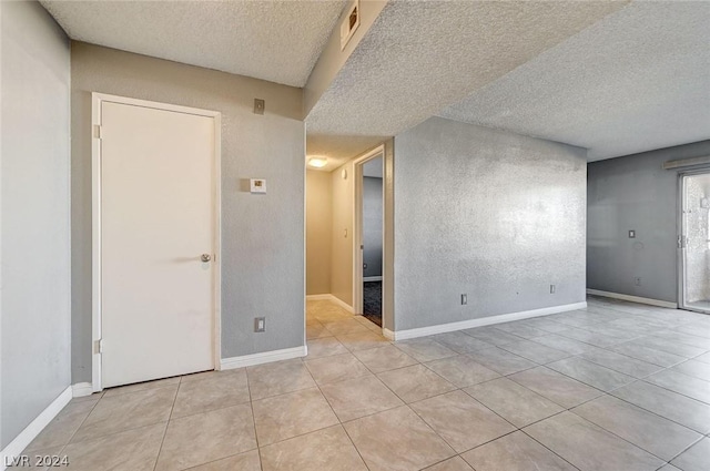 tiled spare room featuring a textured ceiling