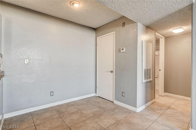 corridor featuring a textured ceiling and light tile patterned flooring