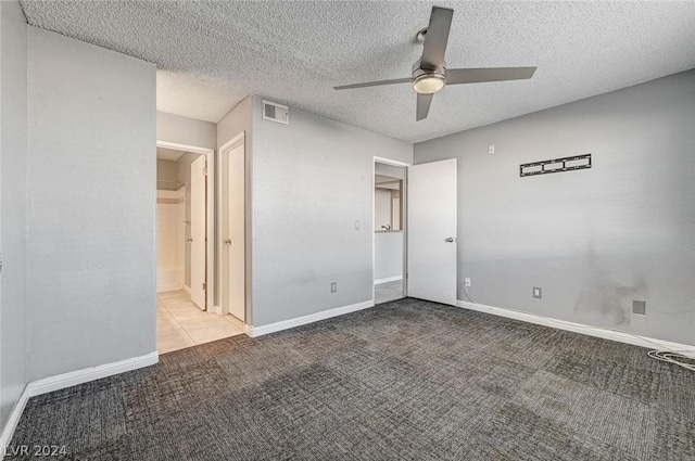 unfurnished bedroom featuring carpet, a textured ceiling, ceiling fan, and ensuite bath