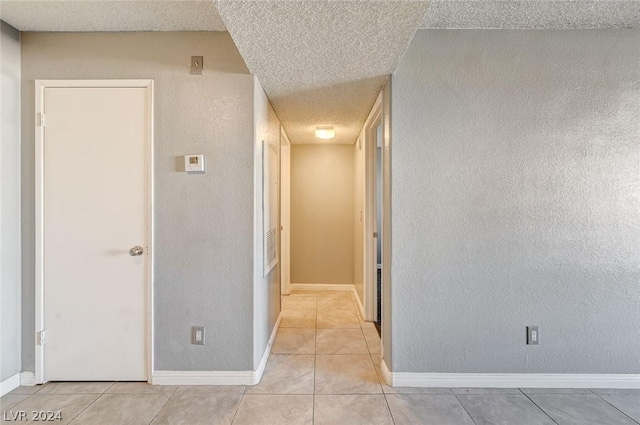 hallway with light tile patterned floors and a textured ceiling