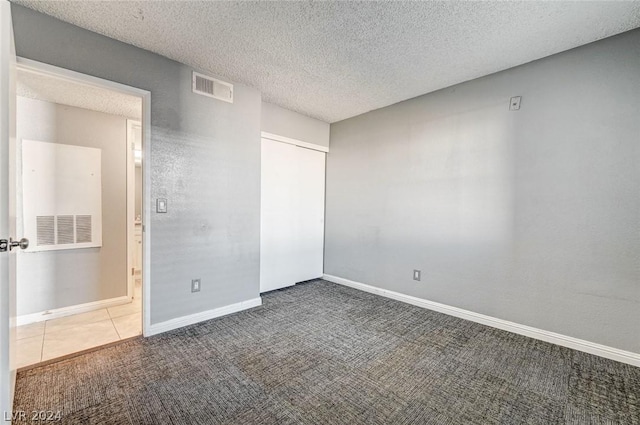 carpeted empty room featuring a textured ceiling