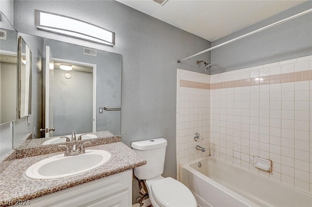 full bathroom with tiled shower / bath, vanity, and toilet