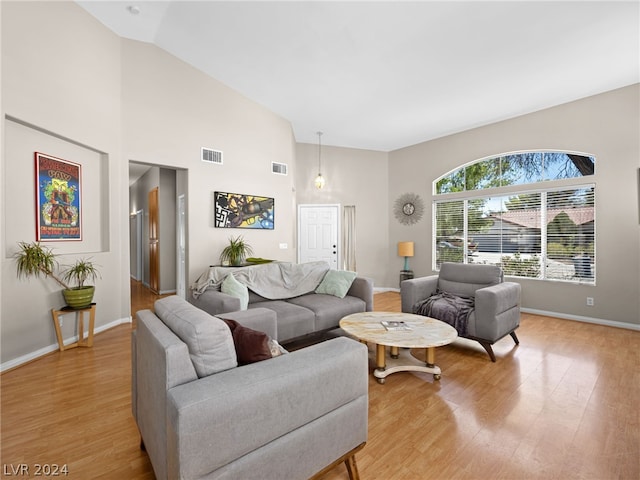 living room with light hardwood / wood-style floors and high vaulted ceiling