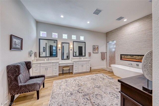 bathroom featuring dual vanity, a bathtub, a fireplace, and wood-type flooring