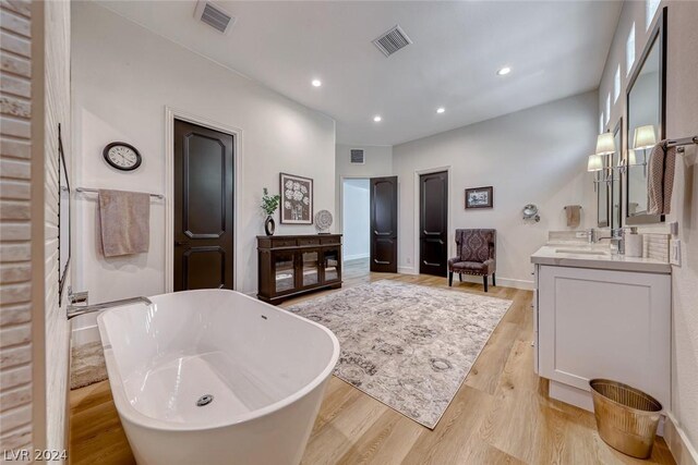 bathroom featuring vanity with extensive cabinet space, hardwood / wood-style flooring, and a bathing tub